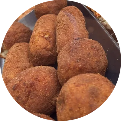 Arancini e crocchè dorati nel vassoio della vetrina