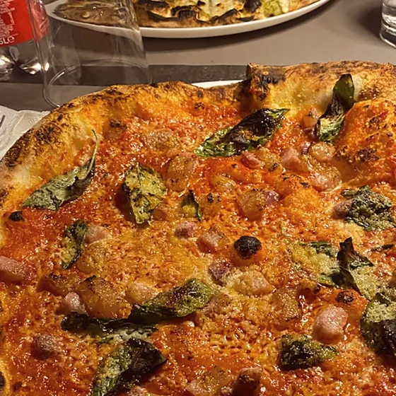 Pizza rossa con pancetta e basilico sul tavolo