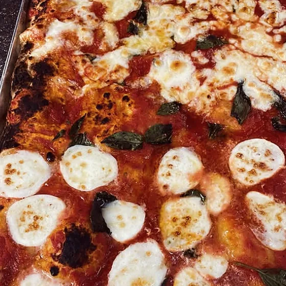 Pizza margherita in teglia con fior di latte e basilico appena sfornata